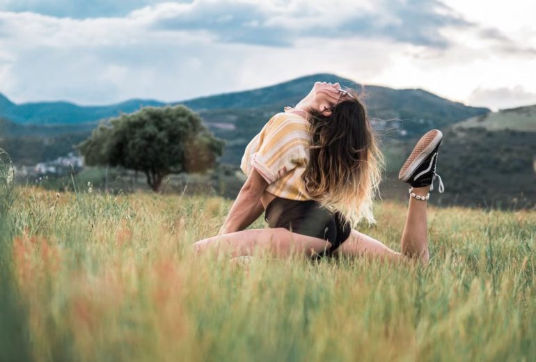 A young woman posing elegantly in a scenic countryside setting, enjoying nature and freedom.
