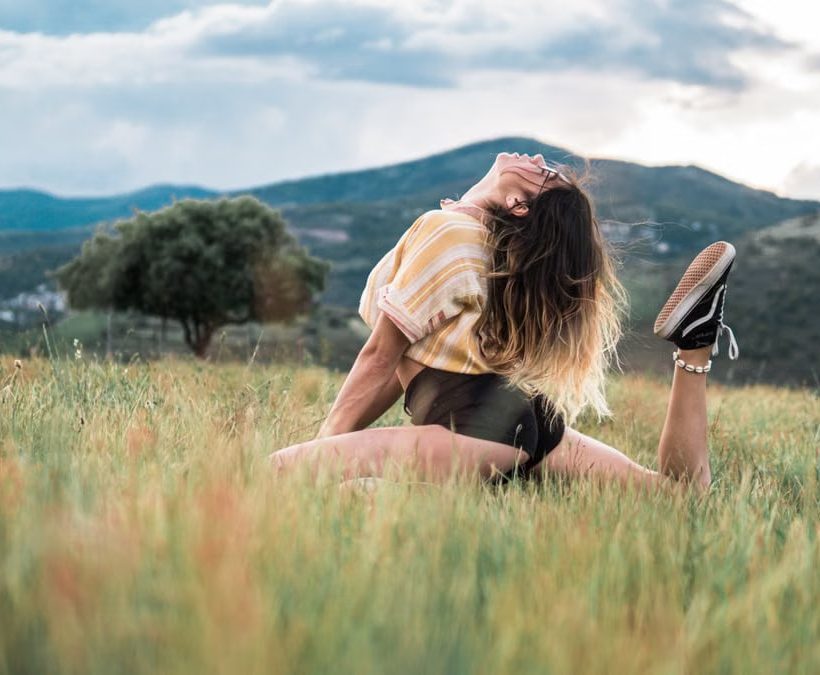 A young woman posing elegantly in a scenic countryside setting, enjoying nature and freedom.