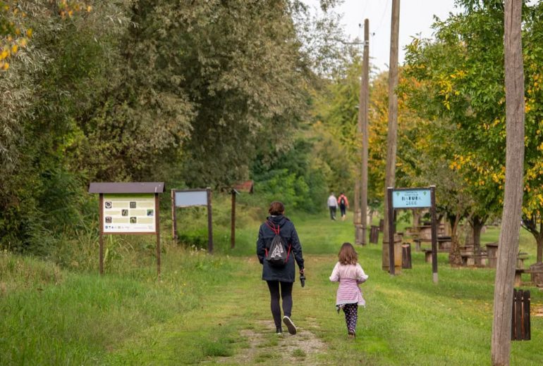A parent and child walking on a path in a scenic nature reserve in Croatia, surrounded by lush greenery.