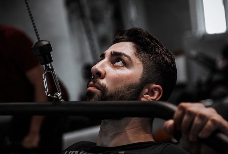 Muscular man working out with determination on gym equipment.