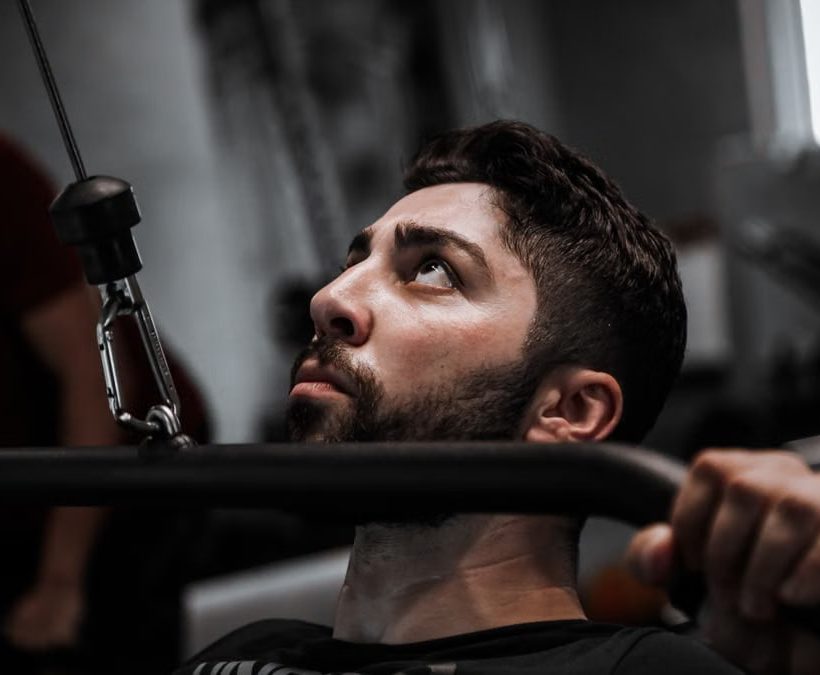 Muscular man working out with determination on gym equipment.